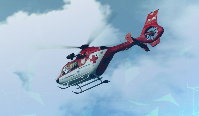 Hintergrund Himmel mit weißen Wolken. Im Vordergrund weiß-roter Rettungshubschrauber mit rotem Kreuz.